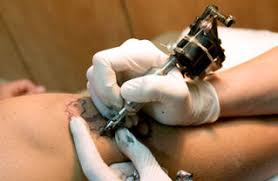 A tattoo artist apply a tattoo wearing gloves